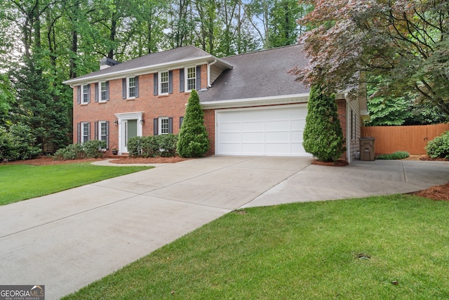colonial house with a garage, concrete driveway, brick siding, and a chimney