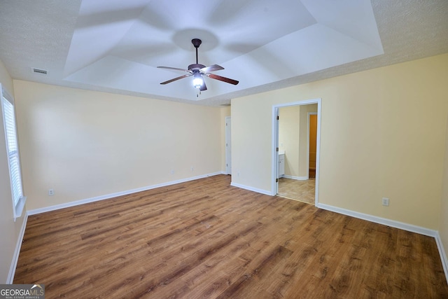 3350 Cooper Woods Dr, Loganville, GA 30052 - unfurnished bedroom with a tray ceiling, wood finished floors, baseboards, ensuite bath, and a ceiling fan