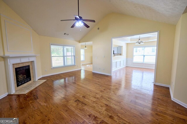 3350 Cooper Woods Dr, Loganville, GA 30052 - unfurnished living room with vaulted ceiling, ceiling fan, wood finished floors, a tiled fireplace, and plenty of natural light