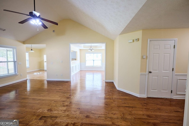 3350 Cooper Woods Dr, Loganville, GA 30052 - unfurnished living room with dark wood finished floors, a ceiling fan, vaulted ceiling, a chandelier, and a textured ceiling