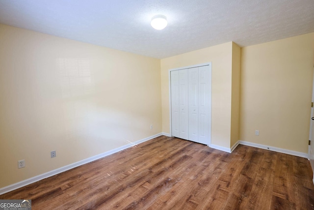 3350 Cooper Woods Dr, Loganville, GA 30052 - unfurnished bedroom featuring wood finished floors, a closet, baseboards, and a textured ceiling