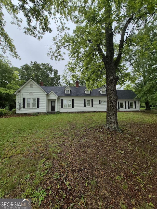 view of front of home featuring a chimney and a front lawn