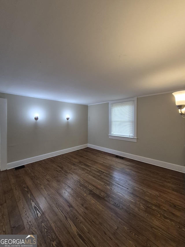 empty room featuring dark wood-style flooring, baseboards, and a chandelier