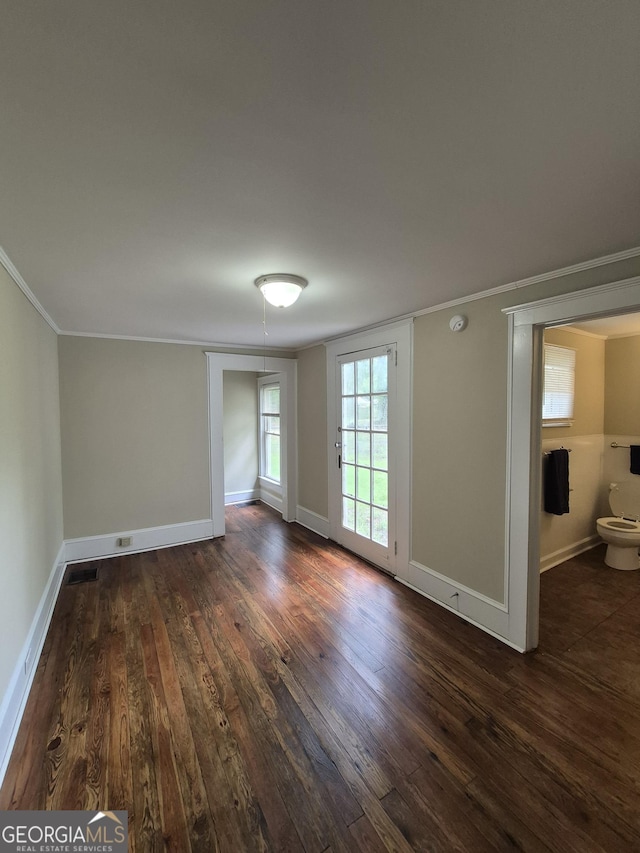unfurnished room with dark wood-style floors, ornamental molding, and baseboards