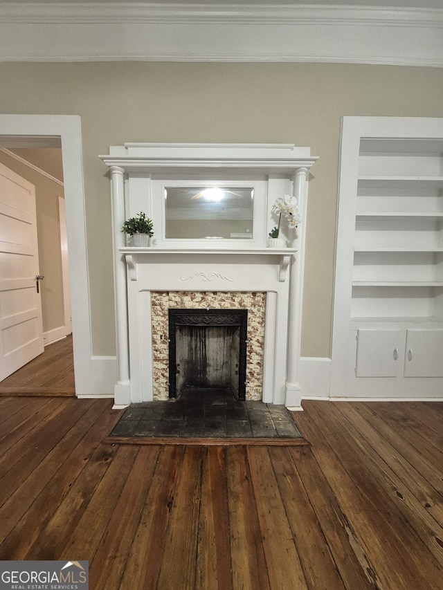 detailed view of crown molding, wood finished floors, a fireplace, baseboards, and built in features