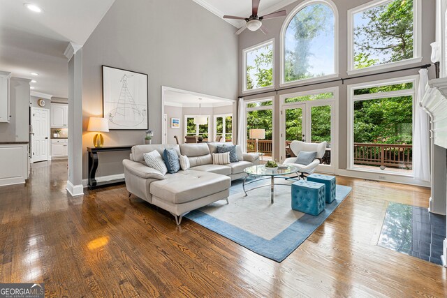 living room featuring a towering ceiling, crown molding, ceiling fan, and dark wood-style floors