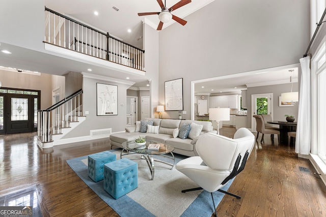 living room with a high ceiling, dark wood-style floors, a ceiling fan, baseboards, and stairway