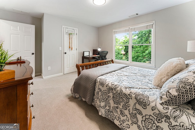 bedroom with light colored carpet, baseboards, and an office area