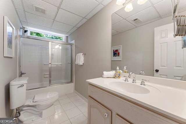 full bathroom featuring toilet, tile patterned flooring, vanity, a drop ceiling, and enclosed tub / shower combo