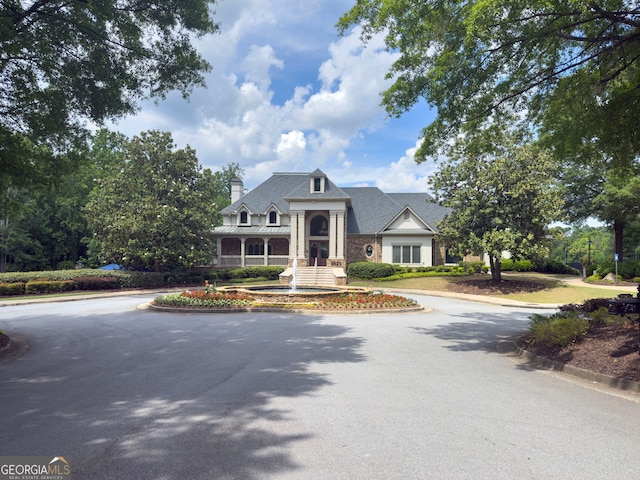 view of front facade featuring curved driveway, a standing seam roof, and a chimney