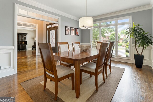 dining room with wood finished floors, crown molding, a wainscoted wall, and french doors