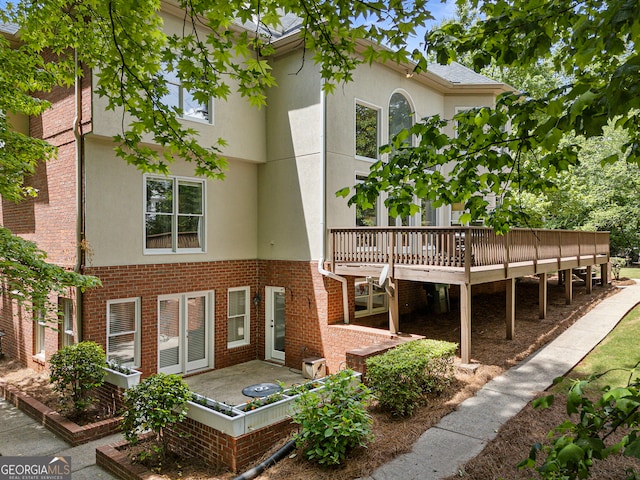 rear view of property with stucco siding, a deck, and brick siding