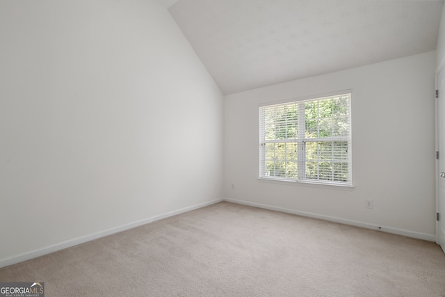 unfurnished room featuring light colored carpet, baseboards, and lofted ceiling