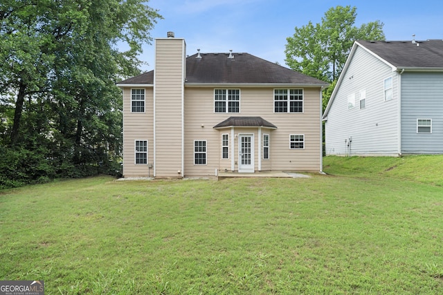 rear view of house featuring a patio, a chimney, and a yard