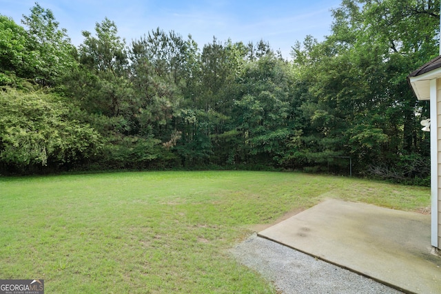view of green lawn with a patio area