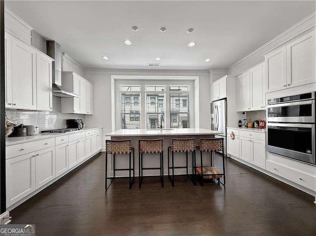 1127 Provence Ln, Decatur, GA 30033 - kitchen with stainless steel appliances, wall chimney exhaust hood, a kitchen bar, white cabinets, and ornamental molding