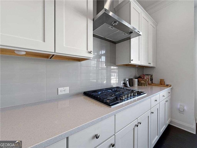 1127 Provence Ln, Decatur, GA 30033 - kitchen featuring wall chimney range hood, stainless steel gas cooktop, white cabinetry, tasteful backsplash, and crown molding