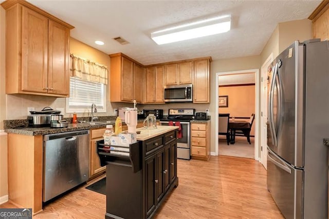 3265 Watson Gate Rd, Loganville, GA 30052 - kitchen featuring appliances with stainless steel finishes, a sink, light wood finished floors, recessed lighting, and a center island