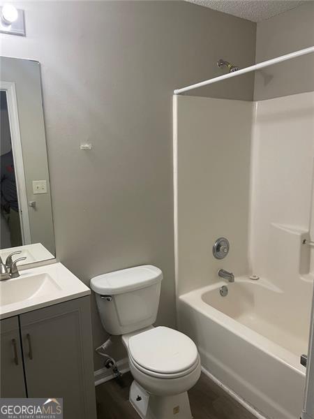 248 Dreamland Cir, Winder, GA 30680 - full bathroom with toilet, washtub / shower combination, vanity, wood finished floors, and a textured ceiling