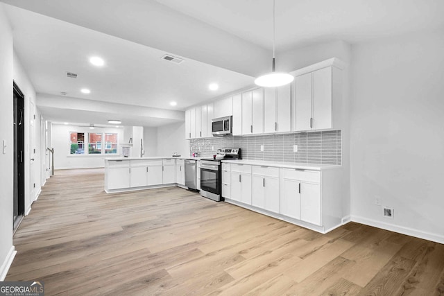 kitchen with appliances with stainless steel finishes, a peninsula, baseboards, light wood-type flooring, and recessed lighting