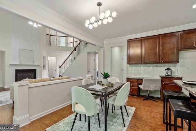 3153 Daleview Way SW, Atlanta, GA 30331 - dining space with ornamental molding, light wood-style floors, a chandelier, stairway, and a large fireplace