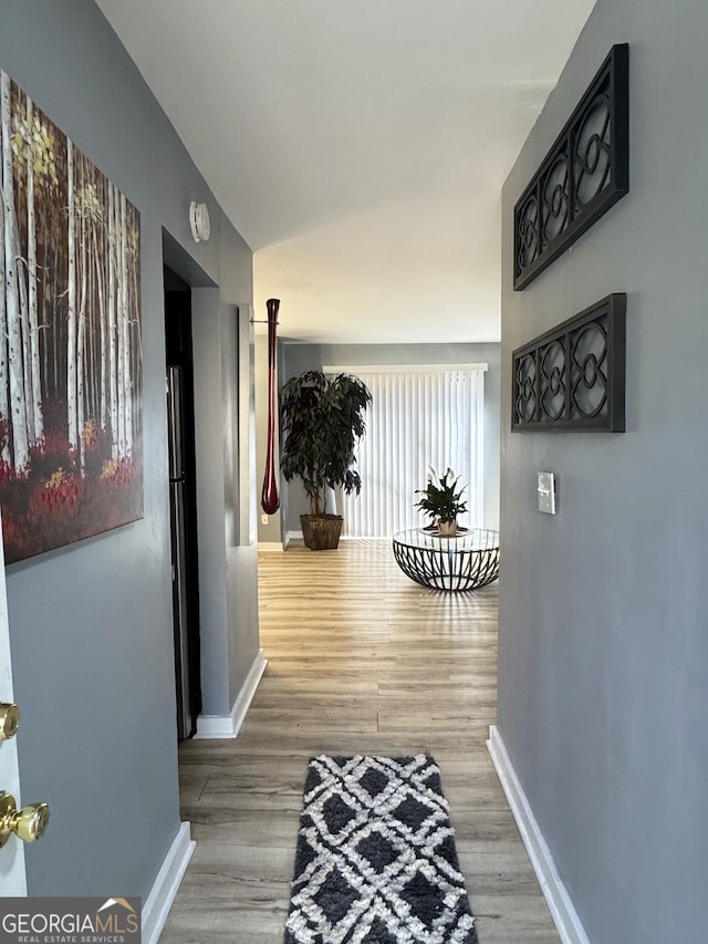 hall with baseboards, wood finished floors, and lofted ceiling