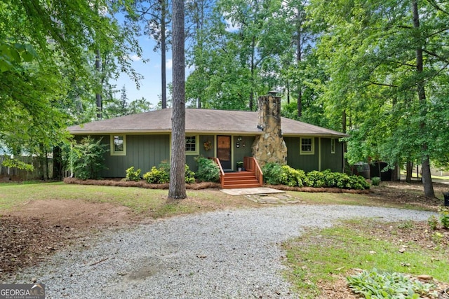 single story home featuring a chimney, fence, and driveway