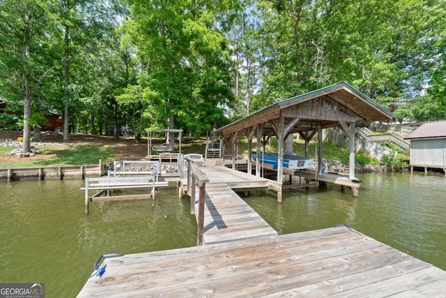 dock featuring a water view, boat lift, and view of scattered trees