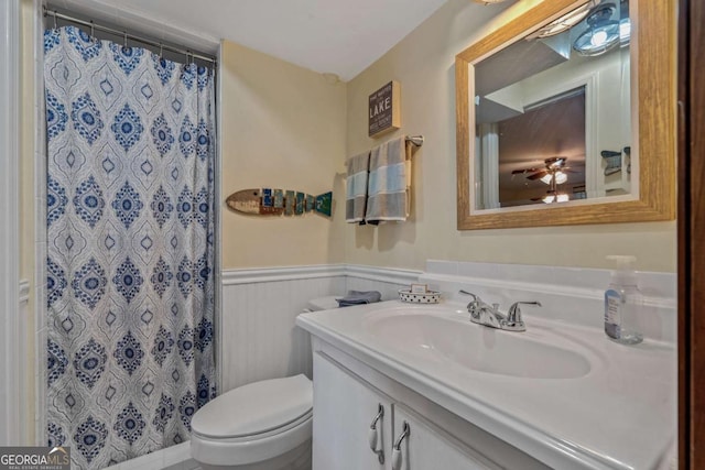 bathroom with toilet, wainscoting, vanity, and a shower with curtain