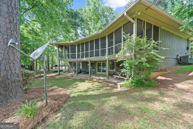 rear view of property with a sunroom, central air condition unit, french doors, and a patio