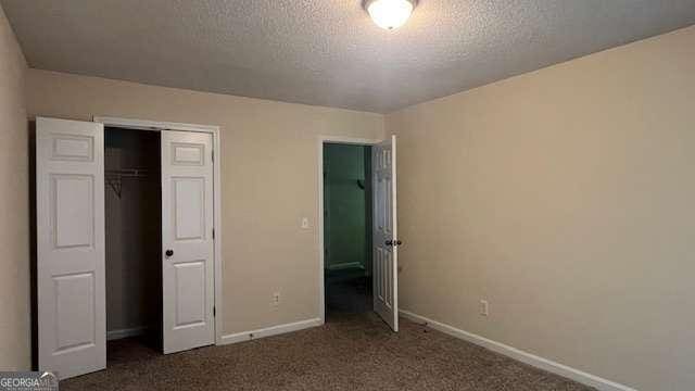 7055 Blairs View Dr Unit 1, Austell, GA 30168 - unfurnished bedroom featuring baseboards, dark carpet, a closet, and a textured ceiling