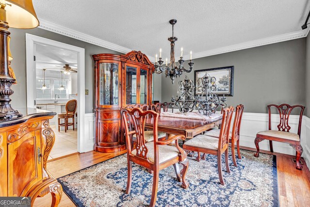 4250 Edgewater Ct NW, Kennesaw, GA 30144 - dining room with crown molding, wainscoting, a chandelier, a textured ceiling, and light wood-style floors