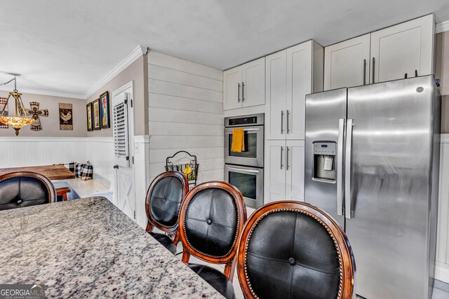 4250 Edgewater Ct NW, Kennesaw, GA 30144 - kitchen with appliances with stainless steel finishes, ornamental molding, white cabinets, light stone countertops, and pendant lighting