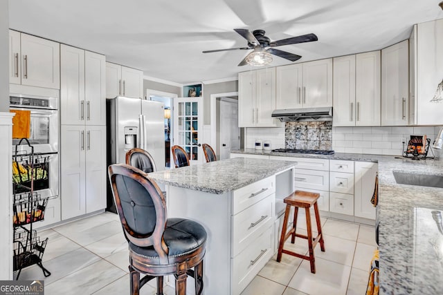 4250 Edgewater Ct NW, Kennesaw, GA 30144 - kitchen featuring stainless steel appliances, a breakfast bar, under cabinet range hood, ceiling fan, and tasteful backsplash