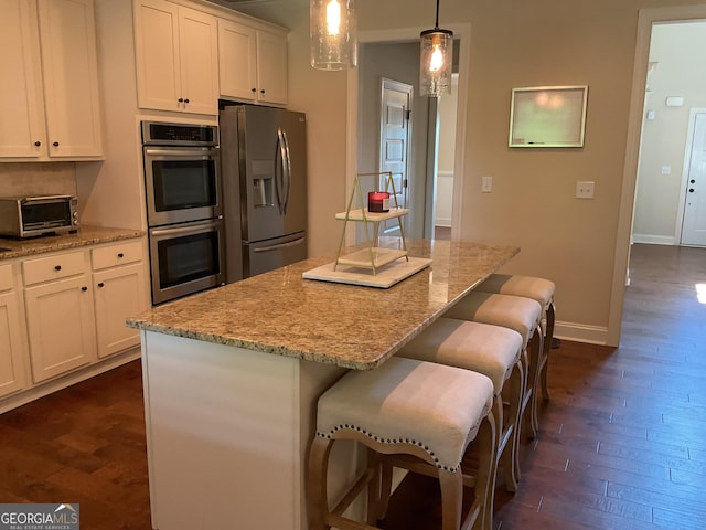 101 Elkins Blvd, Locust Grove, GA 30248 - kitchen featuring appliances with stainless steel finishes, dark wood-type flooring, a center island, and light stone countertops