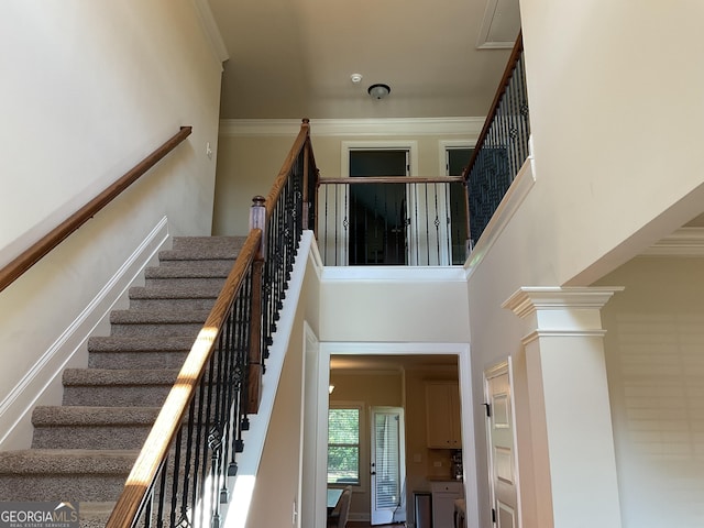 stairway featuring ornamental molding and a towering ceiling