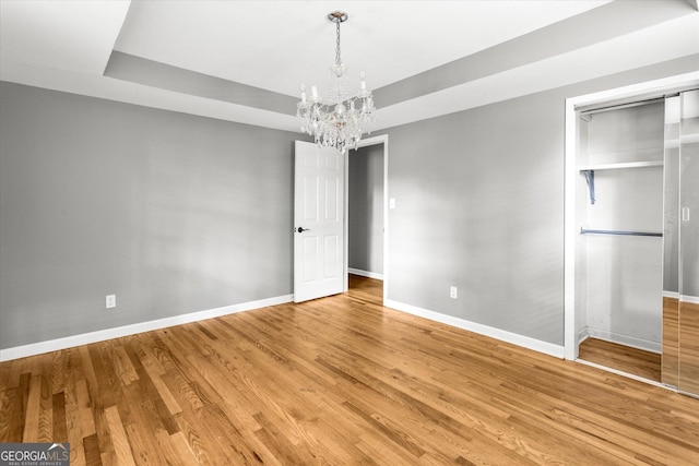 125 Sycamore Dr, Athens, GA 30606 - spare room featuring a chandelier, light wood-style flooring, and a raised ceiling