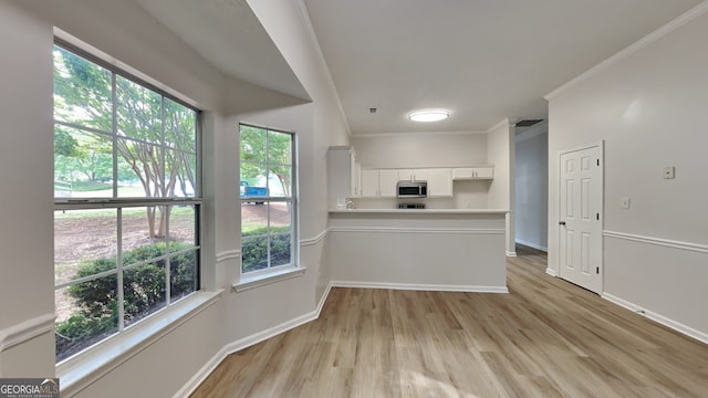 700 Patriots Point St, Locust Grove, GA 30248 - kitchen featuring stainless steel microwave, light wood finished floors, white cabinets, baseboards, and ornamental molding