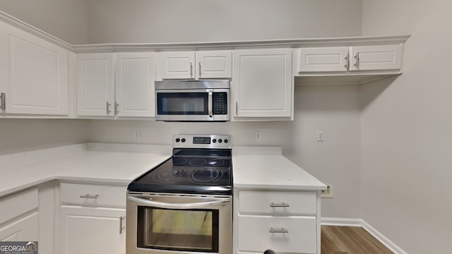 700 Patriots Point St, Locust Grove, GA 30248 - kitchen featuring stainless steel appliances, wood finished floors, white cabinets, and baseboards
