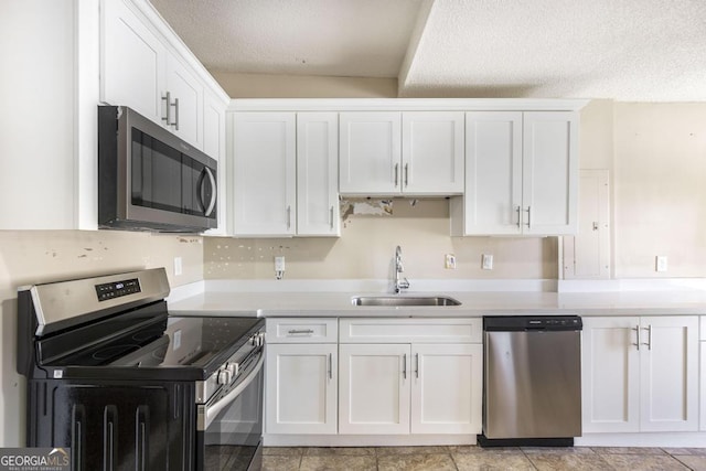 611 Monroe St, Macon, GA 31201 - kitchen featuring appliances with stainless steel finishes, a sink, white cabinetry, a textured ceiling, and light countertops