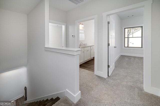 corridor with carpet, baseboards, and a sink