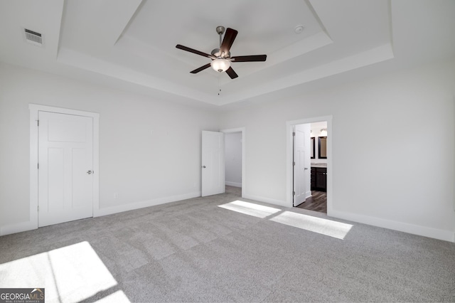 unfurnished bedroom featuring a raised ceiling, carpet, and ensuite bath