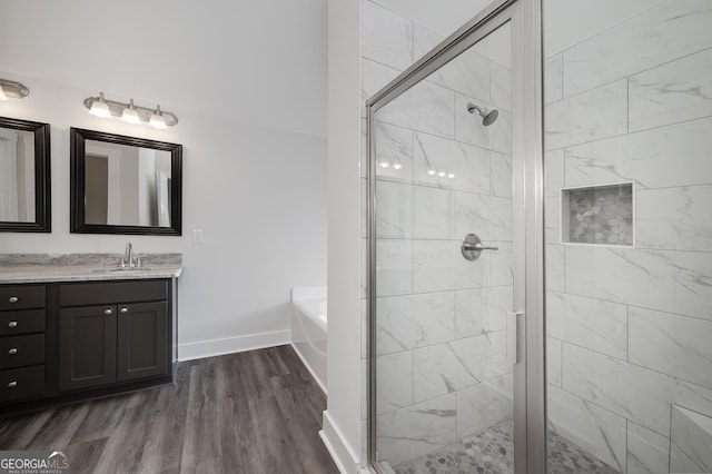 bathroom featuring a shower stall, a garden tub, vanity, and wood finished floors