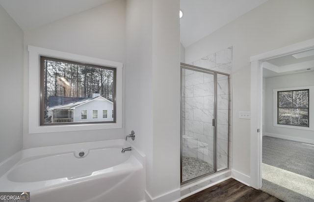 full bathroom featuring lofted ceiling, a stall shower, a garden tub, baseboards, and wood finished floors