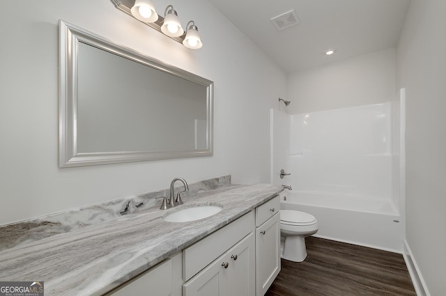 bathroom featuring wood finished floors, toilet, vanity, and shower / bathtub combination