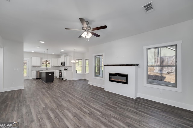 unfurnished living room with a glass covered fireplace, ceiling fan, baseboards, and recessed lighting