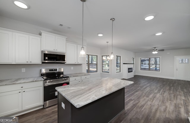 kitchen featuring stainless steel appliances, a kitchen island, a ceiling fan, white cabinetry, and baseboards