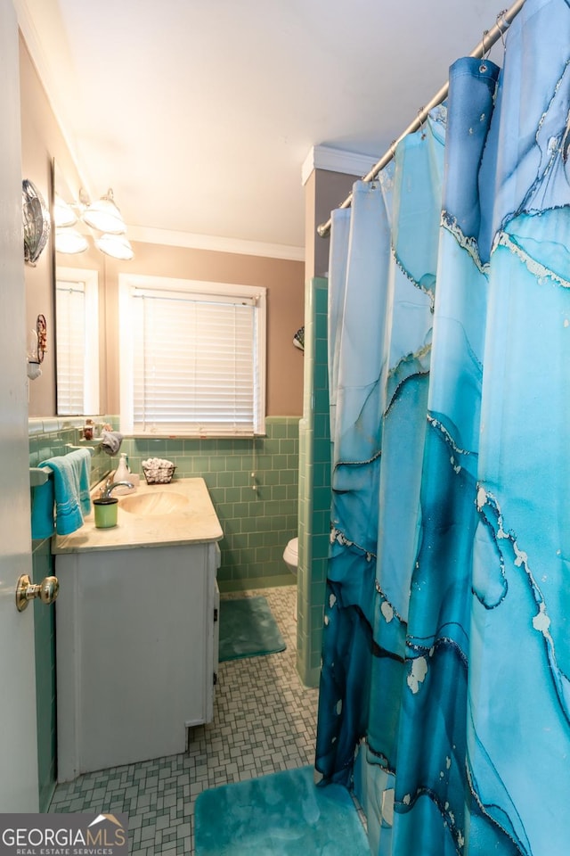 bathroom with ornamental molding, vanity, wainscoting, tile walls, and a shower with curtain