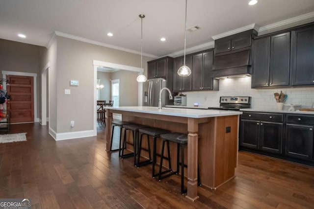 kitchen featuring appliances with stainless steel finishes, a center island with sink, custom exhaust hood, baseboards, and crown molding