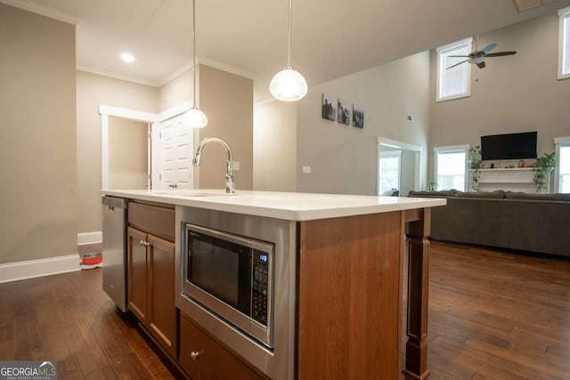 kitchen with stainless steel appliances, dark wood finished floors, a sink, crown molding, and light countertops